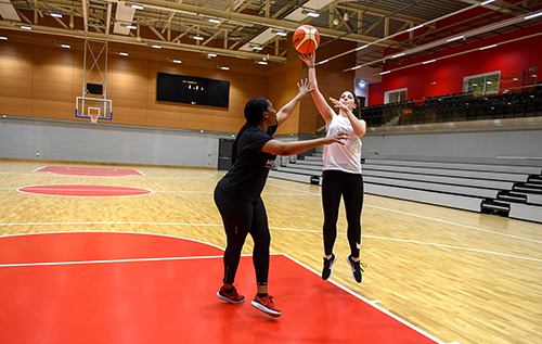 Two women playing basketball together in the high performance sports hall at the Solent Sports Complex