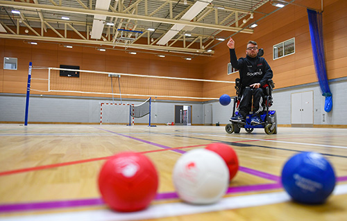 A man in a wheelchair playing sports in the multi-purpose sports hall at the Solent Sports Complex